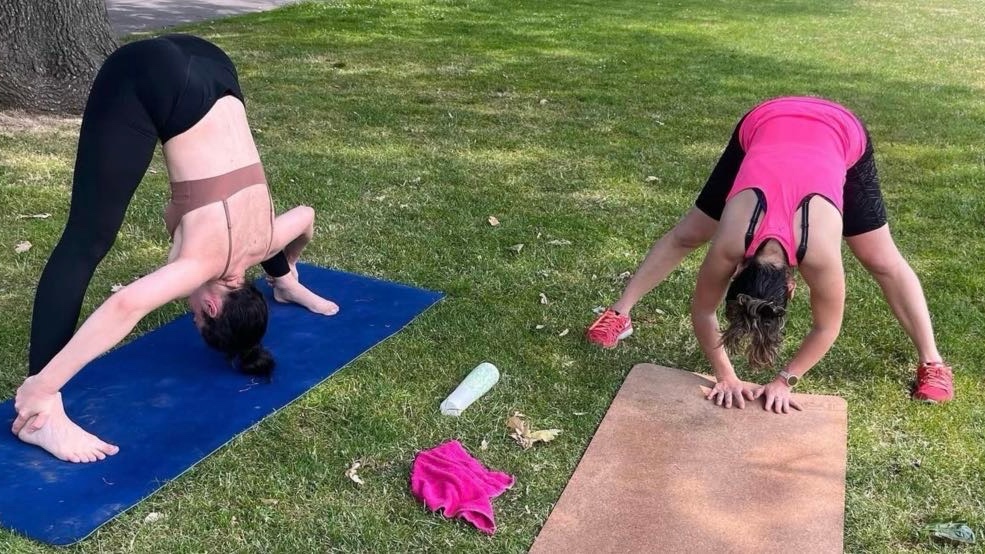 Two women stretching during a group fitness session at Central Park East Ham London